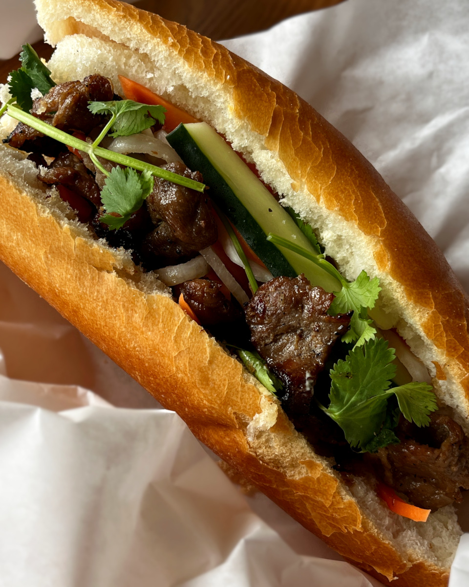 grilled pork banh mi sandwich with pickled vegetables and cilantro