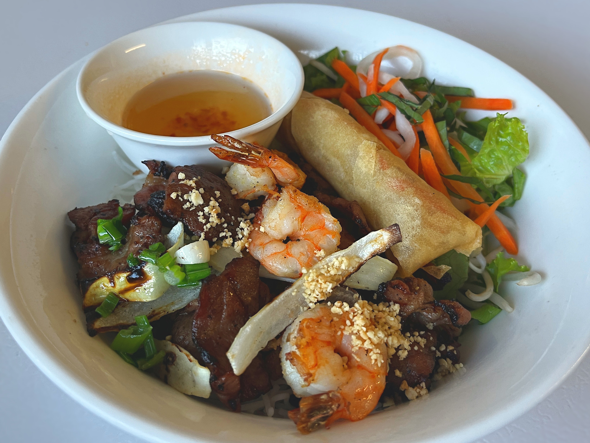Rice vermicelli bowl with grilled pork, shrimp, and an egg roll