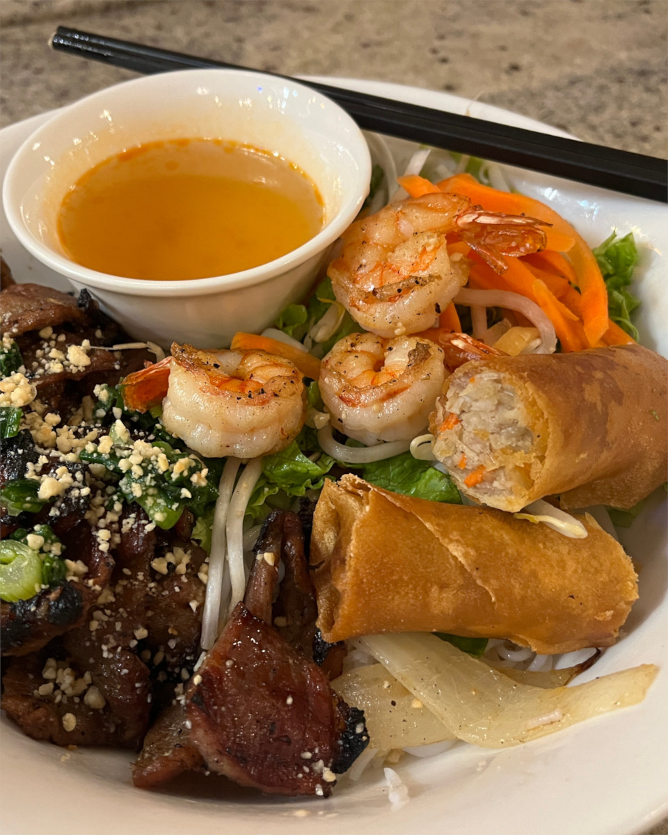 Grilled pork and shrimp over vermicelli with a crispy egg roll, vegetables, and dipping sauce